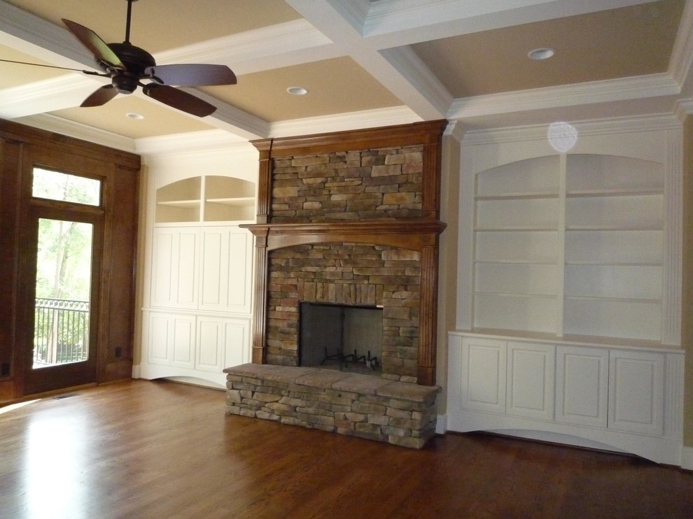 This is an example of a mid-sized traditional formal open concept living room in Other with brown walls, medium hardwood floors, a wood stove, a stone fireplace surround and a concealed tv.