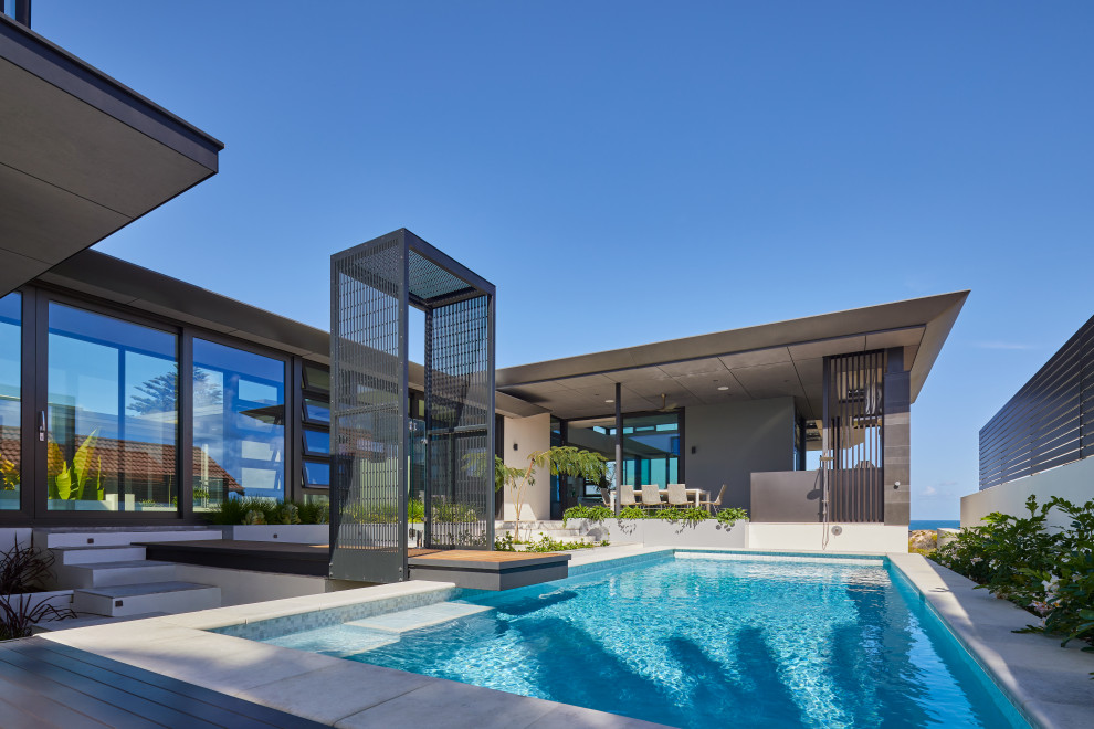 Large contemporary side yard rectangular aboveground pool in Perth with a pool house and concrete pavers.