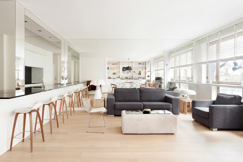 Photo of a large scandinavian open concept living room in Paris with white walls, light hardwood floors, no fireplace, no tv and a library.