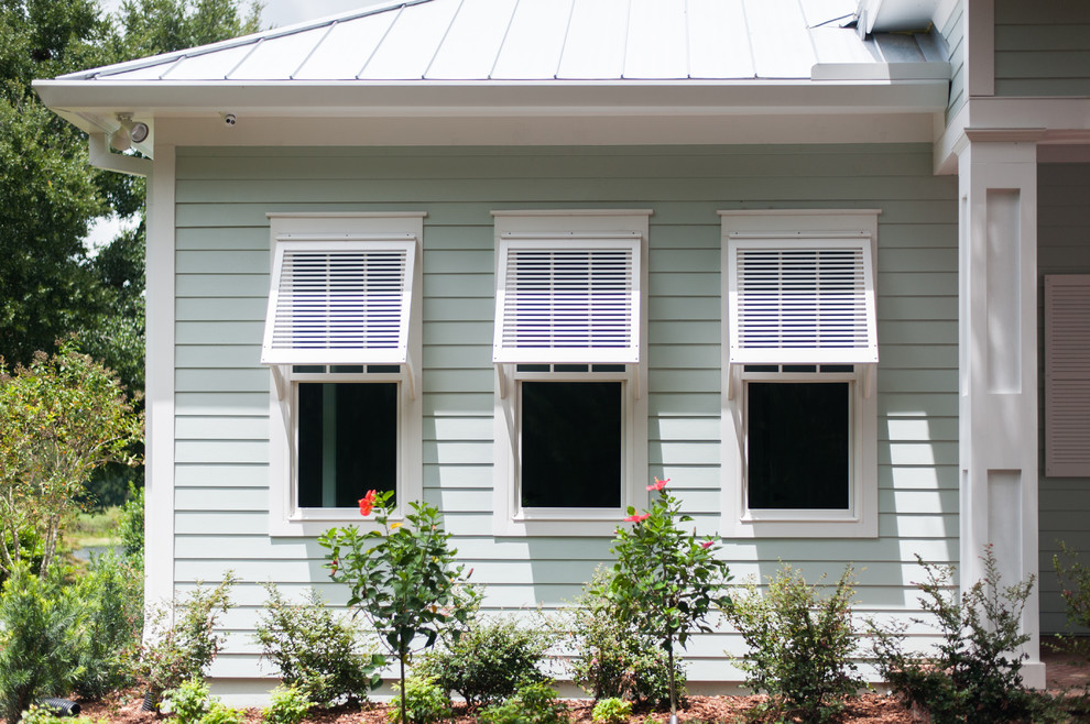 This is an example of a large beach style one-storey white house exterior in Orlando with vinyl siding and a metal roof.