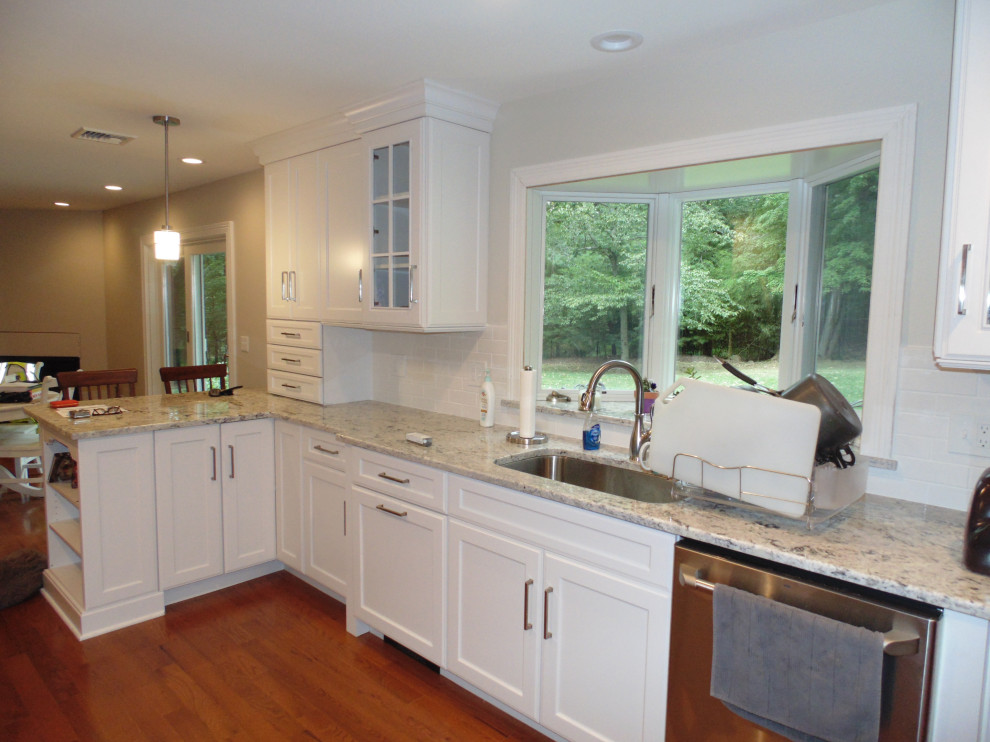 Mid-sized transitional medium tone wood floor and brown floor eat-in kitchen photo with an undermount sink, recessed-panel cabinets, white cabinets, granite countertops, white backsplash, subway tile backsplash, stainless steel appliances, no island and white countertops