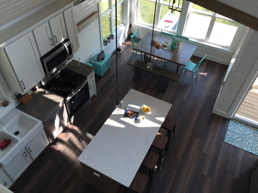 Open concept kitchen - mid-sized transitional u-shaped dark wood floor and brown floor open concept kitchen idea with a farmhouse sink, shaker cabinets, white cabinets, quartz countertops, white backsplash, stainless steel appliances, an island and white countertops