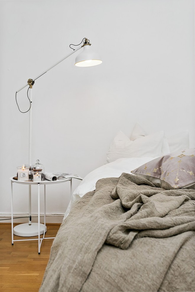 Scandinavian bedroom in Malmo with white walls, medium hardwood floors and beige floor.