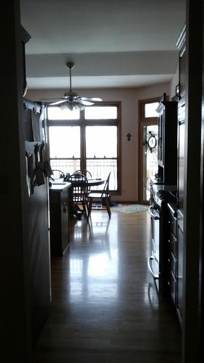 Open concept kitchen - transitional l-shaped light wood floor open concept kitchen idea in Milwaukee with a farmhouse sink, shaker cabinets, medium tone wood cabinets, granite countertops, gray backsplash, glass tile backsplash, stainless steel appliances and an island