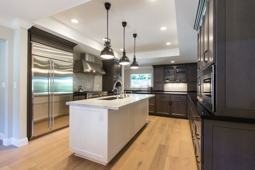 Photo of a mid-sized transitional u-shaped open plan kitchen in Sacramento with an undermount sink, shaker cabinets, grey cabinets, marble benchtops, white splashback, stone tile splashback, stainless steel appliances, light hardwood floors and with island.