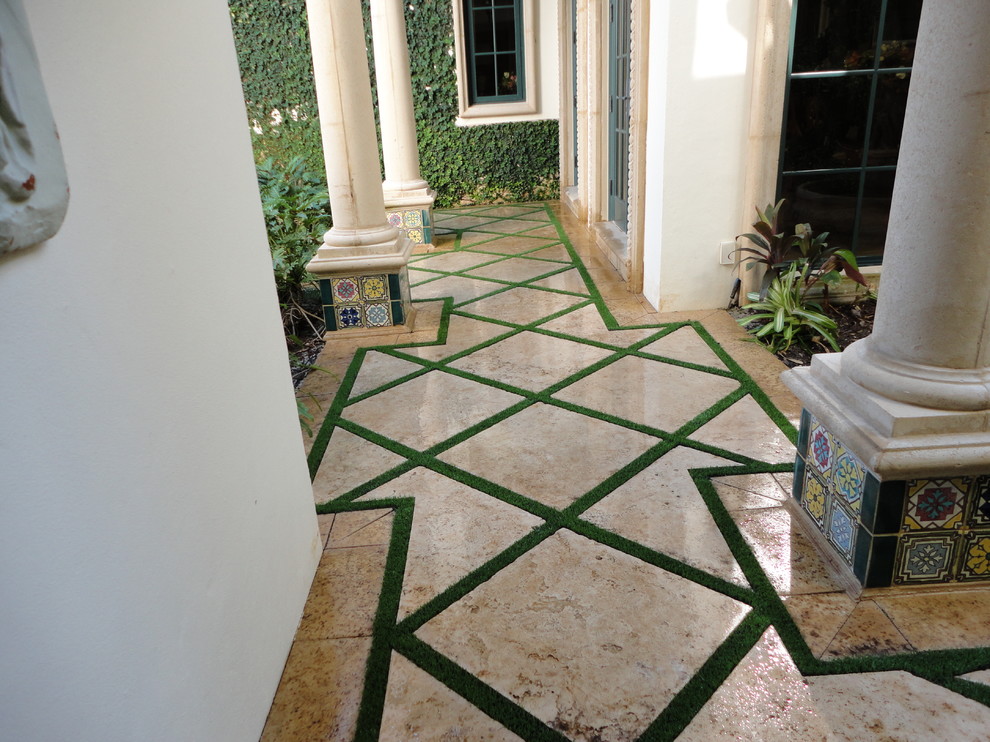 Mid-sized mediterranean backyard patio in Miami with natural stone pavers and a roof extension.
