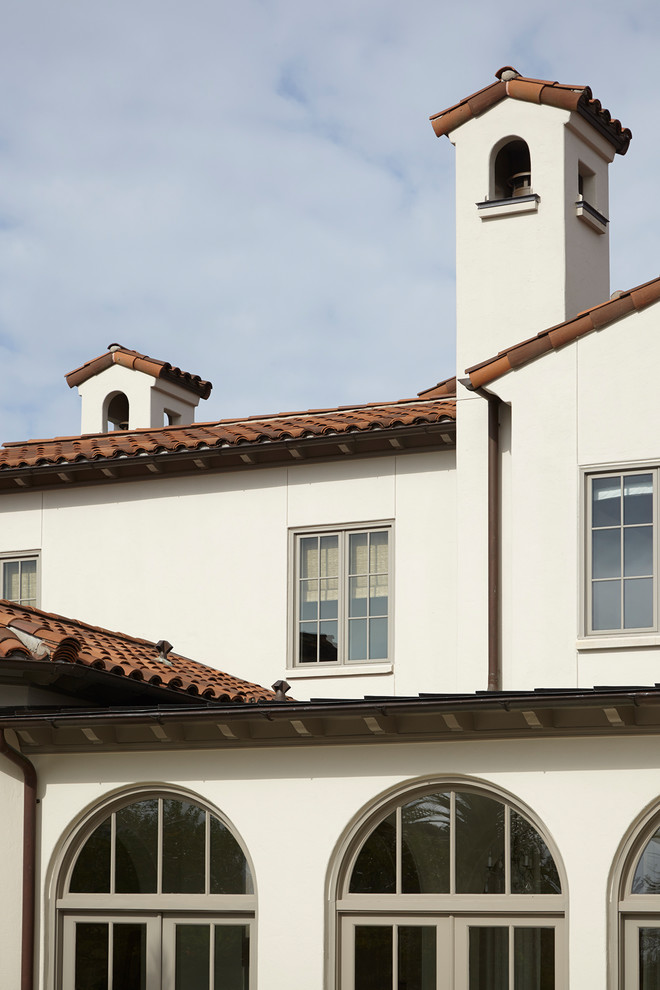 Photo of an expansive mediterranean two-storey stucco white house exterior in Houston with a gable roof and a tile roof.