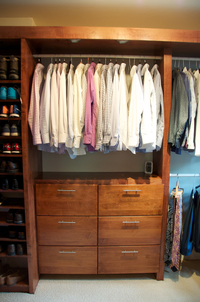 This is an example of a mid-sized contemporary gender-neutral walk-in wardrobe in Jackson with flat-panel cabinets, medium wood cabinets and carpet.