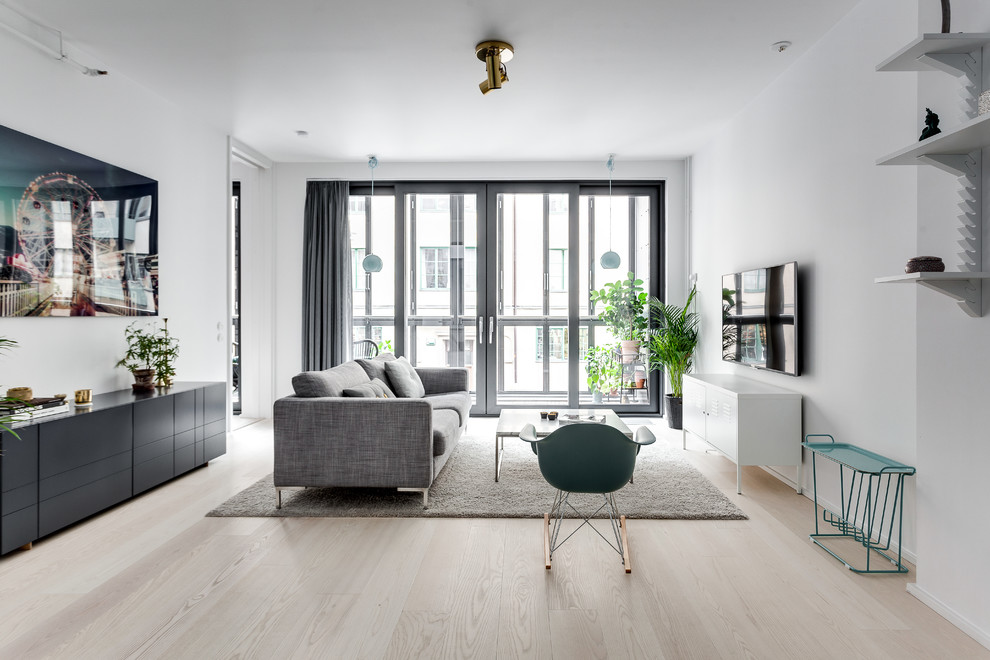 Photo of a mid-sized scandinavian formal open concept living room in Stockholm with white walls, a wall-mounted tv and light hardwood floors.