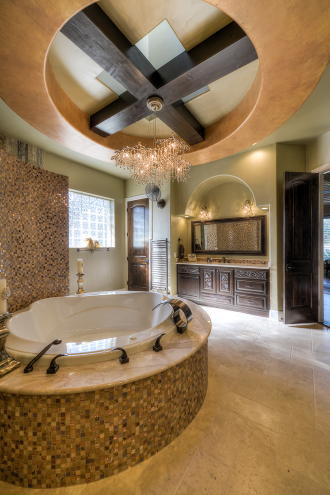 Mediterranean bathroom in Austin with dark wood cabinets, a drop-in tub, multi-coloured tile, mosaic tile and raised-panel cabinets.