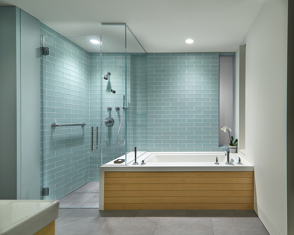 This is an example of a mid-sized contemporary master bathroom in DC Metro with flat-panel cabinets, medium wood cabinets, an alcove shower, blue tile, glass tile, white walls, ceramic floors, an undermount tub, an integrated sink, solid surface benchtops, grey floor and a hinged shower door.