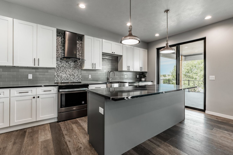 Inspiration for a mid-sized transitional l-shaped laminate floor and brown floor eat-in kitchen remodel with an undermount sink, recessed-panel cabinets, white cabinets, quartz countertops, gray backsplash, porcelain backsplash, black appliances, an island and black countertops