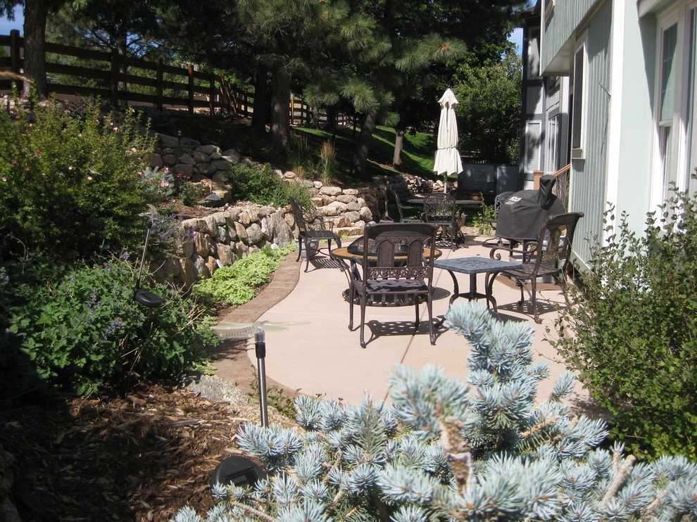 This is an example of a small eclectic backyard patio in Denver with stamped concrete and no cover.