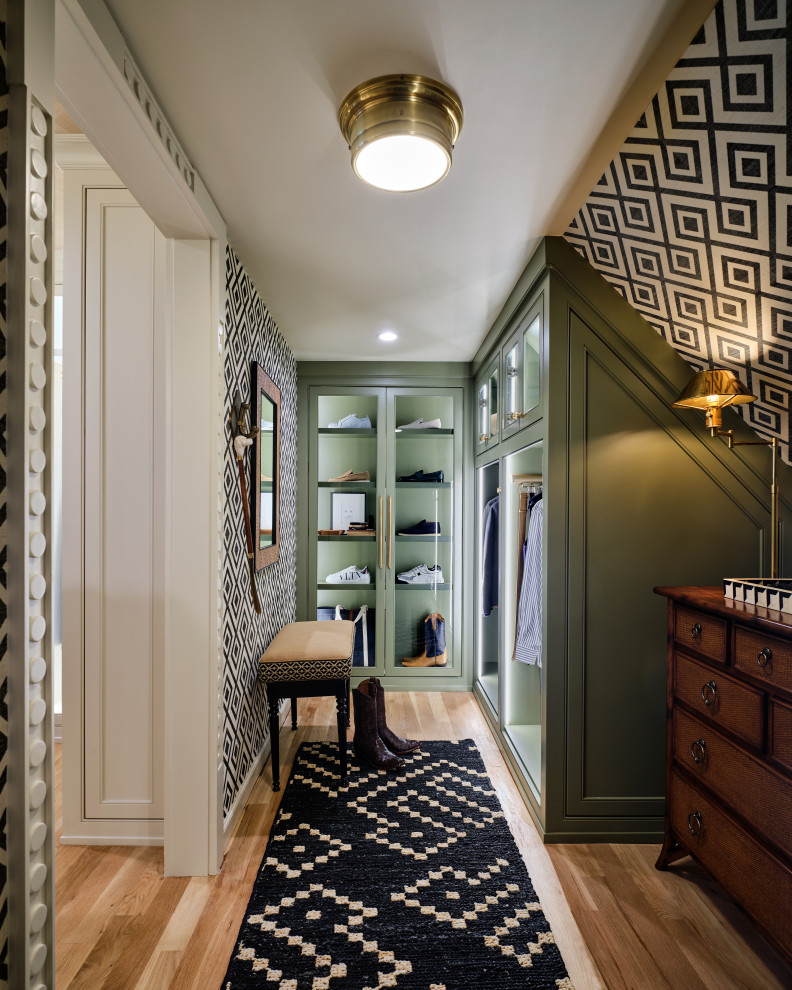 Design ideas for a traditional men's walk-in wardrobe in Dallas with green cabinets, light hardwood floors and glass-front cabinets.