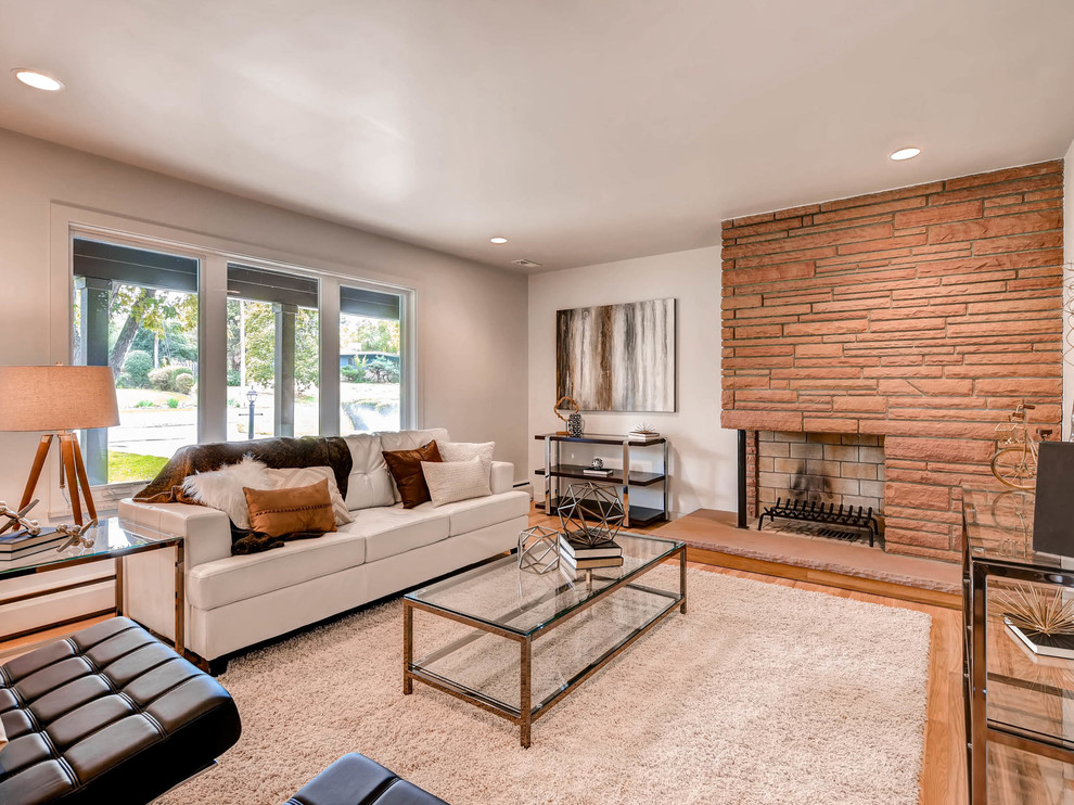 Inspiration for a mid-sized contemporary enclosed living room in Denver with beige walls, light hardwood floors, a standard fireplace, a brick fireplace surround and beige floor.