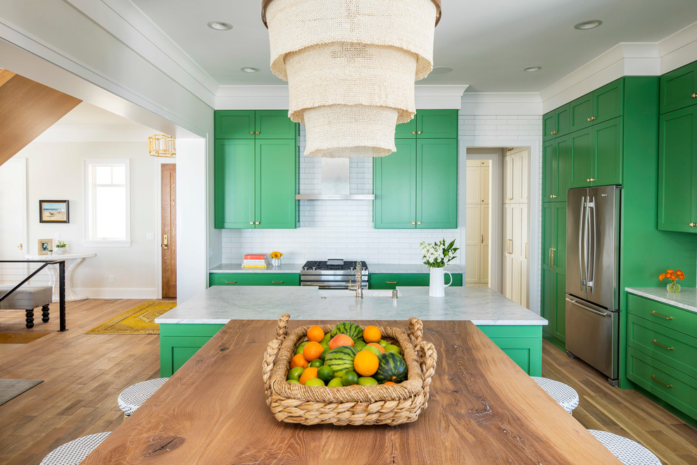 Large beach style l-shaped light wood floor and brown floor open concept kitchen photo in Minneapolis with a farmhouse sink, shaker cabinets, green cabinets, marble countertops, white backsplash, subway tile backsplash, stainless steel appliances and two islands