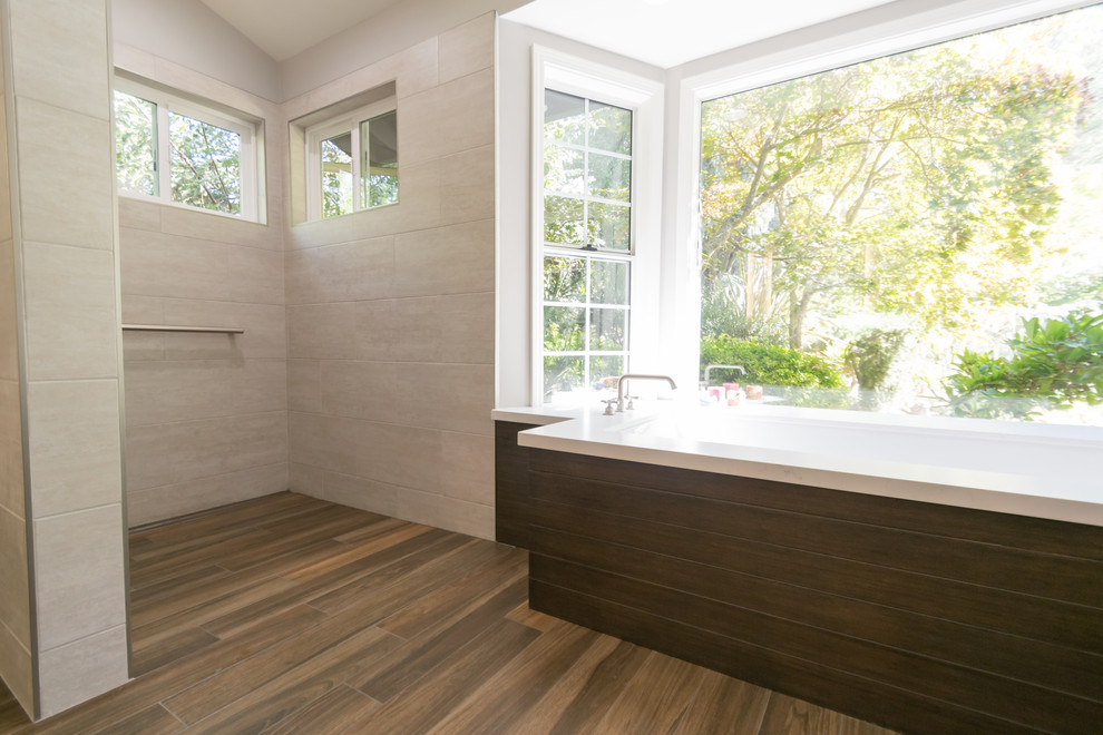 Photo of an expansive contemporary master bathroom in San Francisco with flat-panel cabinets, brown cabinets, an undermount tub, a curbless shower, a bidet, gray tile, beige walls, porcelain floors, an undermount sink, brown floor, an open shower and white benchtops.