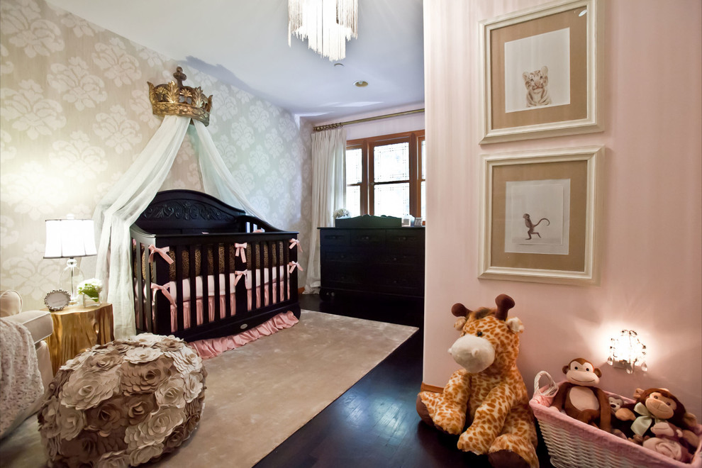 Photo of a nursery for girls in Orange County with pink walls and dark hardwood floors.