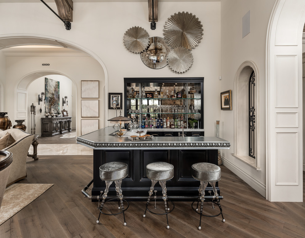 Inspiration for an expansive traditional l-shaped seated home bar in Phoenix with a drop-in sink, open cabinets, black cabinets, zinc benchtops, multi-coloured splashback, mirror splashback, medium hardwood floors, brown floor and grey benchtop.