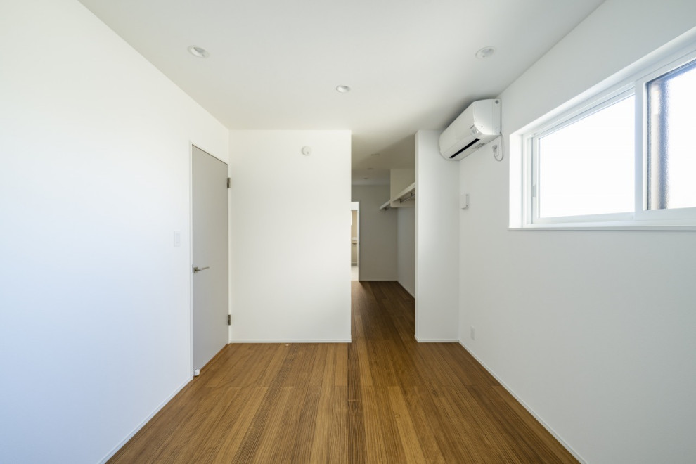 Cette image montre une chambre parentale minimaliste de taille moyenne avec un mur blanc, parquet clair, aucune cheminée, un sol marron, un plafond en papier peint et du papier peint.