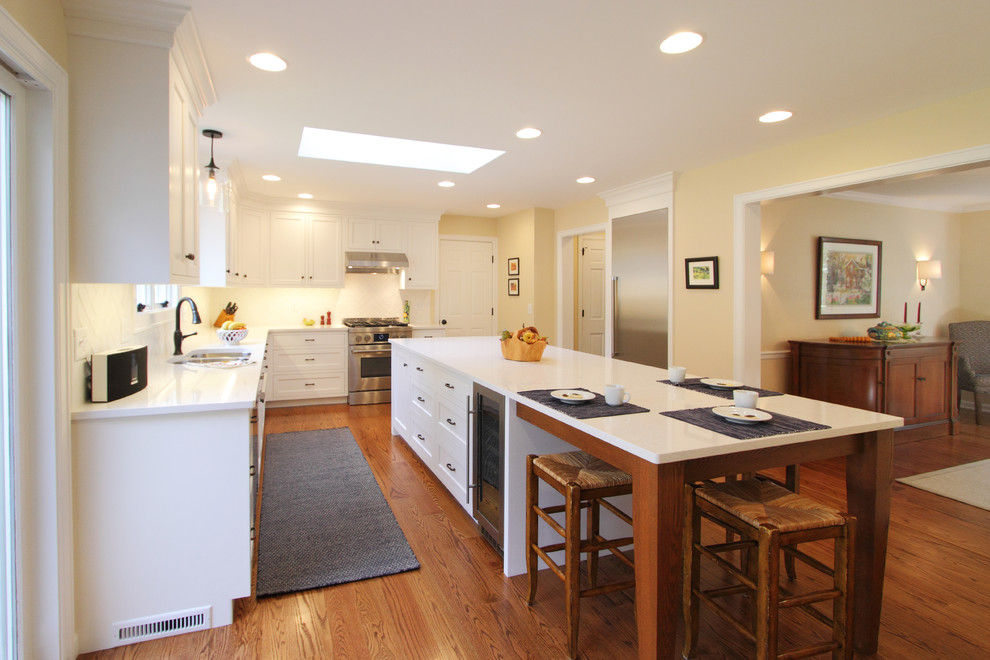 Inspiration for a large transitional l-shaped medium tone wood floor and brown floor enclosed kitchen remodel in Philadelphia with an undermount sink, shaker cabinets, white cabinets, quartz countertops, white backsplash, ceramic backsplash, stainless steel appliances and an island