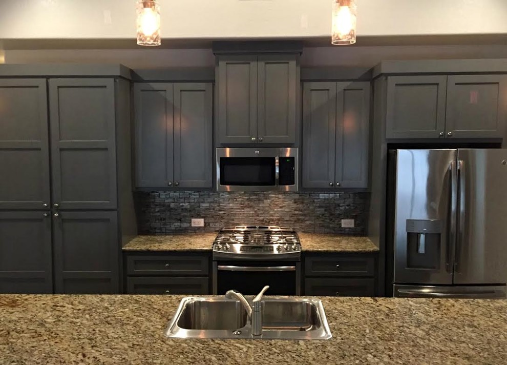 Open concept kitchen - mid-sized transitional galley medium tone wood floor and brown floor open concept kitchen idea in Austin with a double-bowl sink, shaker cabinets, gray cabinets, granite countertops, gray backsplash, glass tile backsplash, stainless steel appliances and an island