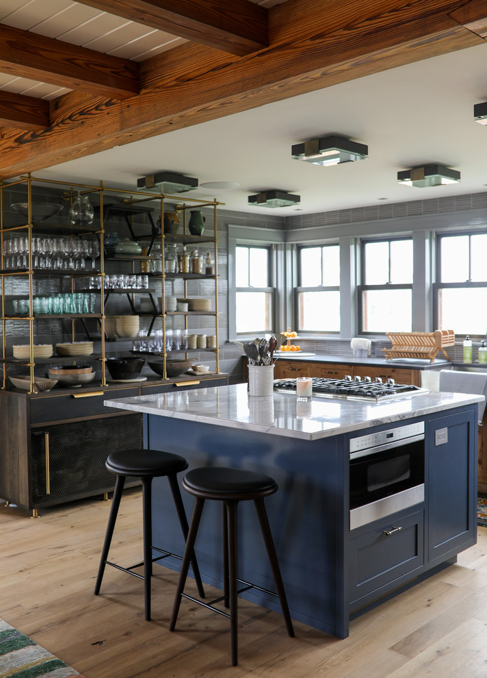 This is an example of a mid-sized country u-shaped eat-in kitchen in Providence with a farmhouse sink, blue cabinets, marble benchtops, grey splashback, porcelain splashback, stainless steel appliances, with island, beige floor, white benchtop, shaker cabinets and light hardwood floors.