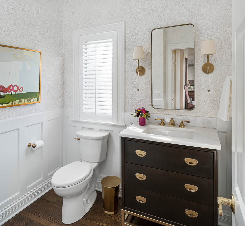 This is an example of a small transitional powder room in Chicago with flat-panel cabinets, dark wood cabinets, an undermount sink, marble benchtops, brown floor, a two-piece toilet, white walls and dark hardwood floors.