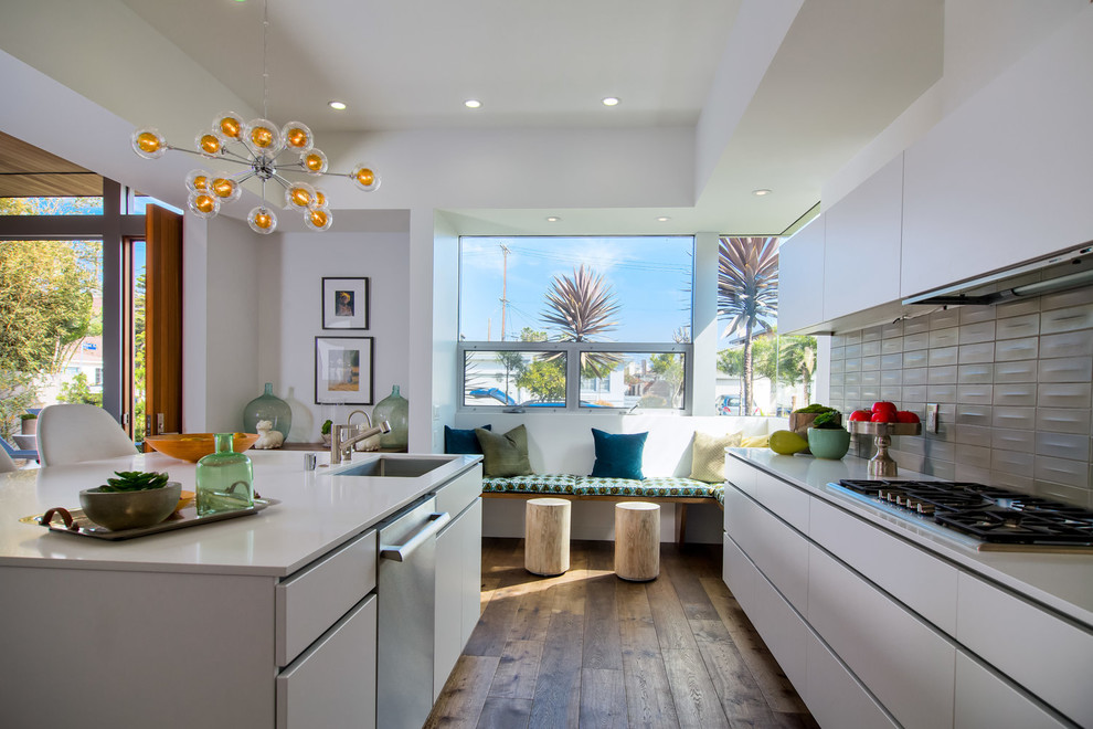 Design ideas for a midcentury kitchen in Los Angeles with an undermount sink, flat-panel cabinets, white cabinets, grey splashback, stainless steel appliances, dark hardwood floors and with island.