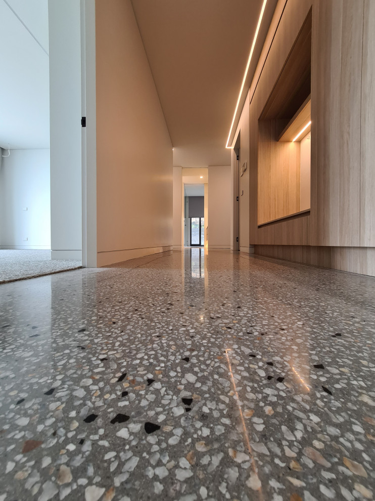 Idée de décoration pour un couloir design de taille moyenne avec un mur blanc, sol en béton ciré, un sol gris et du lambris.