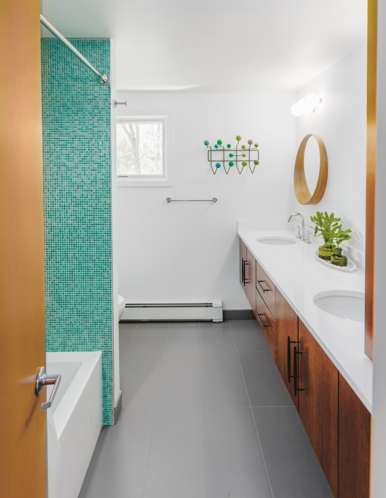 Design ideas for a mid-sized midcentury kids bathroom in Detroit with flat-panel cabinets, brown cabinets, an alcove tub, a shower/bathtub combo, a one-piece toilet, green tile, ceramic tile, white walls, ceramic floors, an undermount sink, quartzite benchtops, grey floor, a shower curtain, white benchtops, a double vanity and a floating vanity.