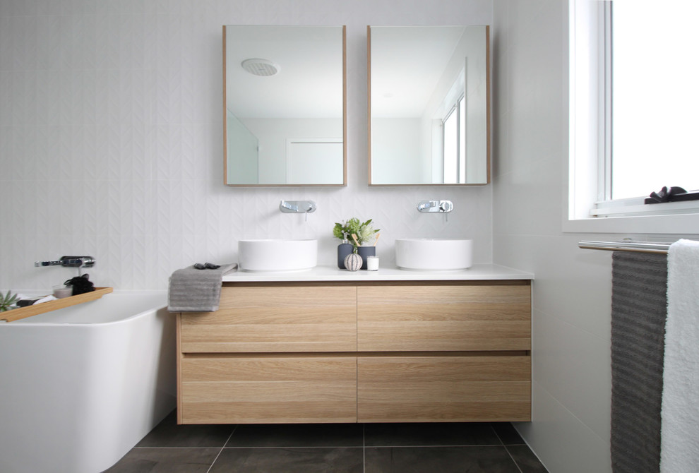 Design ideas for a mid-sized contemporary master bathroom in Brisbane with flat-panel cabinets, light wood cabinets, a freestanding tub, an open shower, a two-piece toilet, white tile, ceramic tile, white walls, porcelain floors, a vessel sink, engineered quartz benchtops, grey floor, an open shower and white benchtops.