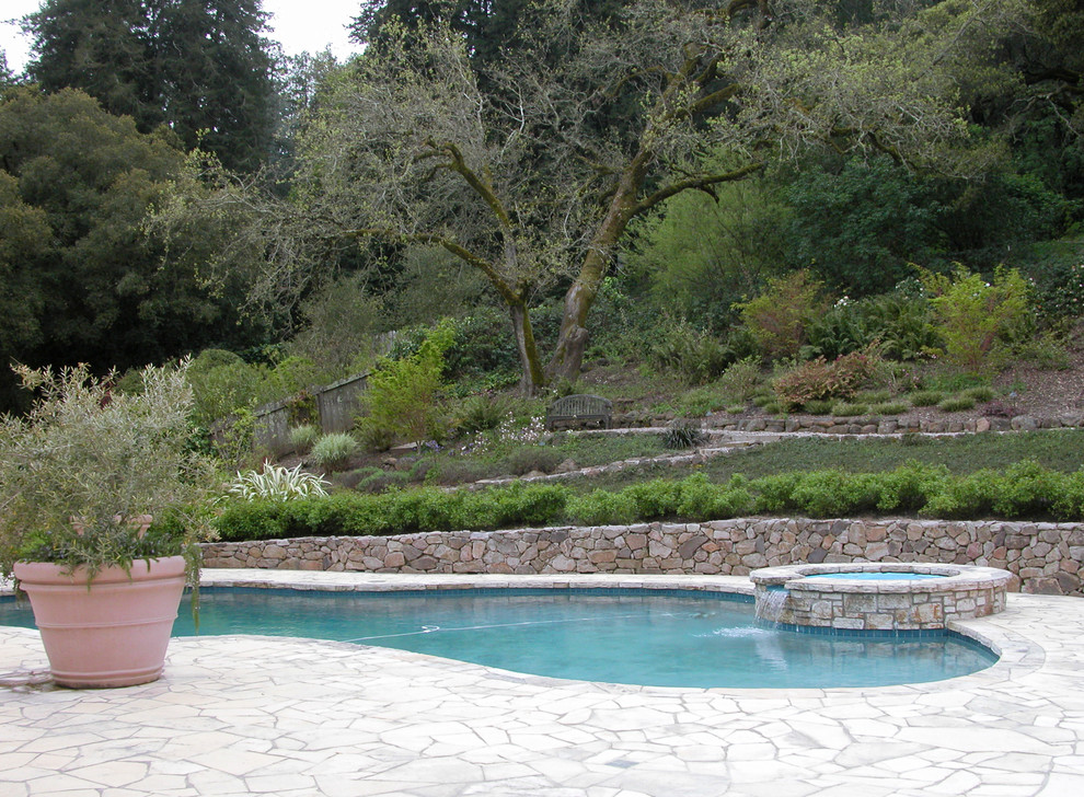 Large traditional custom-shaped pool in Other with natural stone pavers.