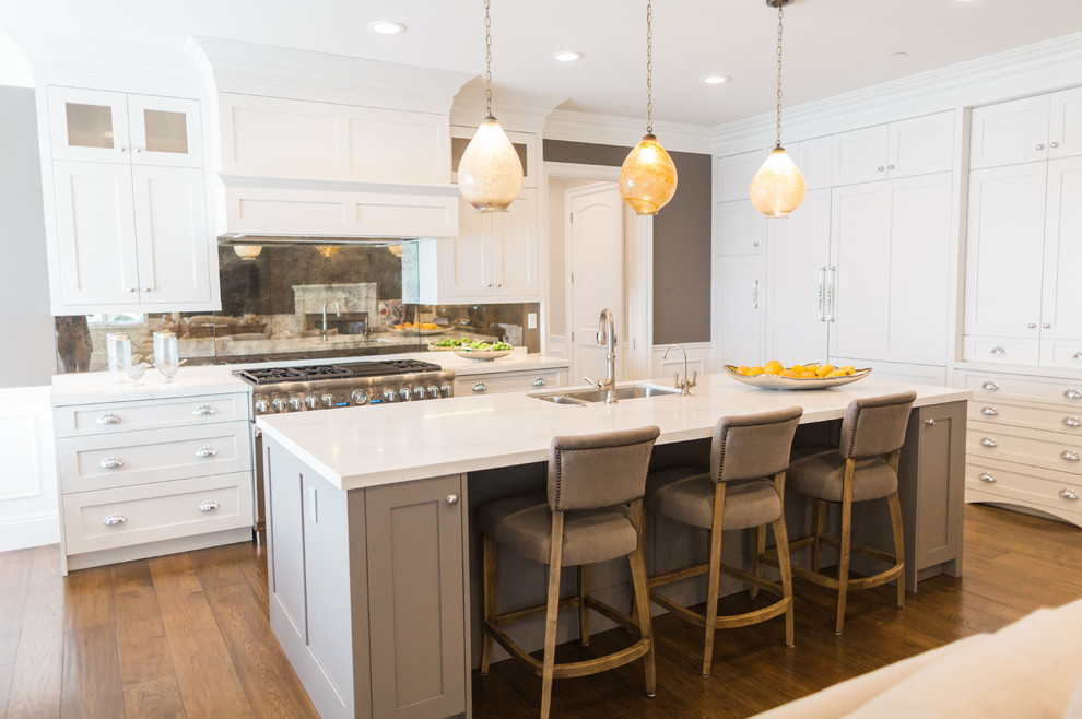 This is an example of a large transitional l-shaped open plan kitchen in San Francisco with an undermount sink, shaker cabinets, white cabinets, quartz benchtops, metallic splashback, metal splashback, stainless steel appliances, medium hardwood floors and with island.
