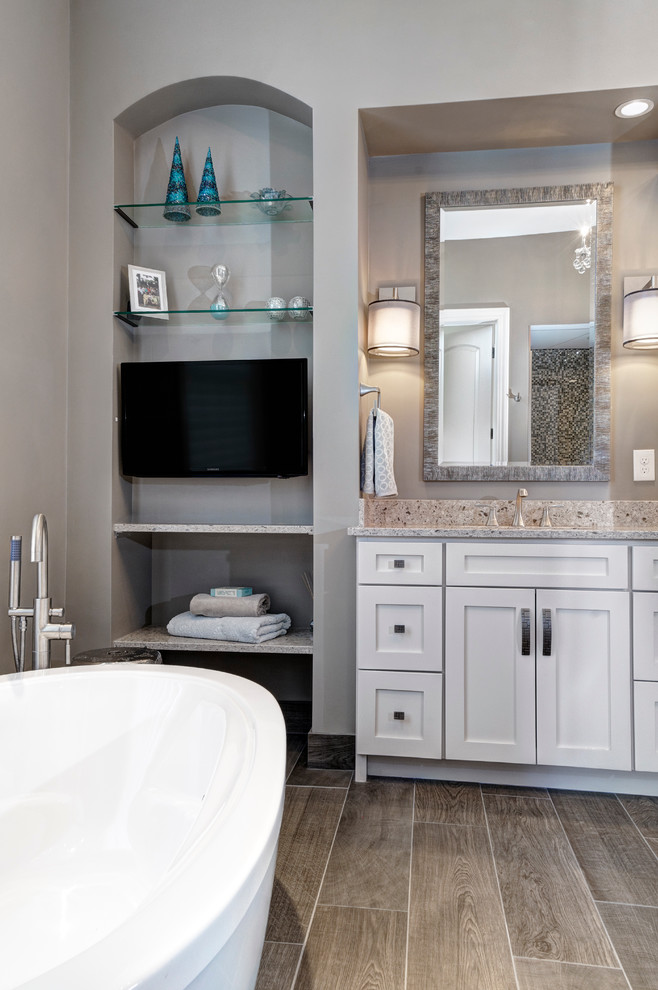This is an example of a transitional master bathroom in Columbus with an undermount sink, white cabinets, engineered quartz benchtops, a freestanding tub, gray tile, wood-look tile, grey walls and ceramic floors.