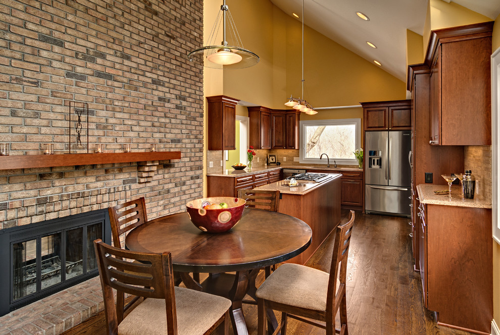 This is an example of a mid-sized arts and crafts u-shaped eat-in kitchen in Minneapolis with an undermount sink, raised-panel cabinets, medium wood cabinets, granite benchtops, beige splashback, stone tile splashback, stainless steel appliances, medium hardwood floors, with island, brown floor and multi-coloured benchtop.