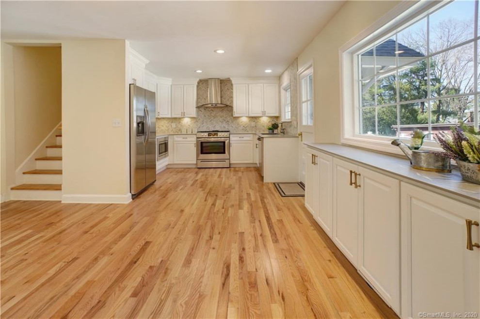 Eat-in kitchen - mid-sized transitional l-shaped light wood floor eat-in kitchen idea with an undermount sink, shaker cabinets, white cabinets, marble backsplash, stainless steel appliances and gray countertops