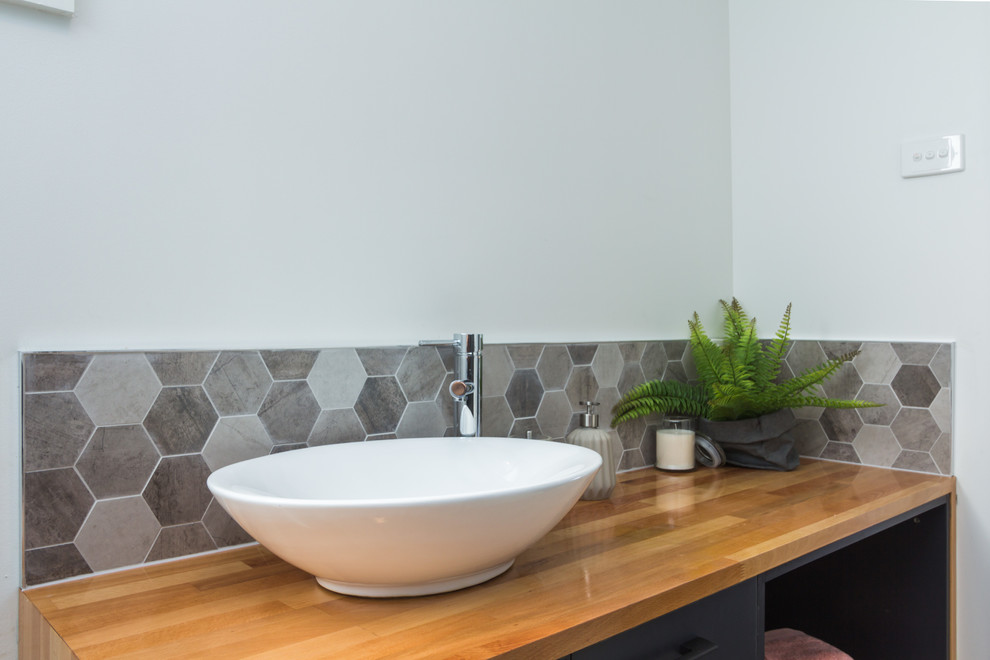 Photo of a mid-sized contemporary master bathroom in Hobart with open cabinets, grey cabinets, multi-coloured tile, ceramic tile, white walls, ceramic floors, a vessel sink and wood benchtops.