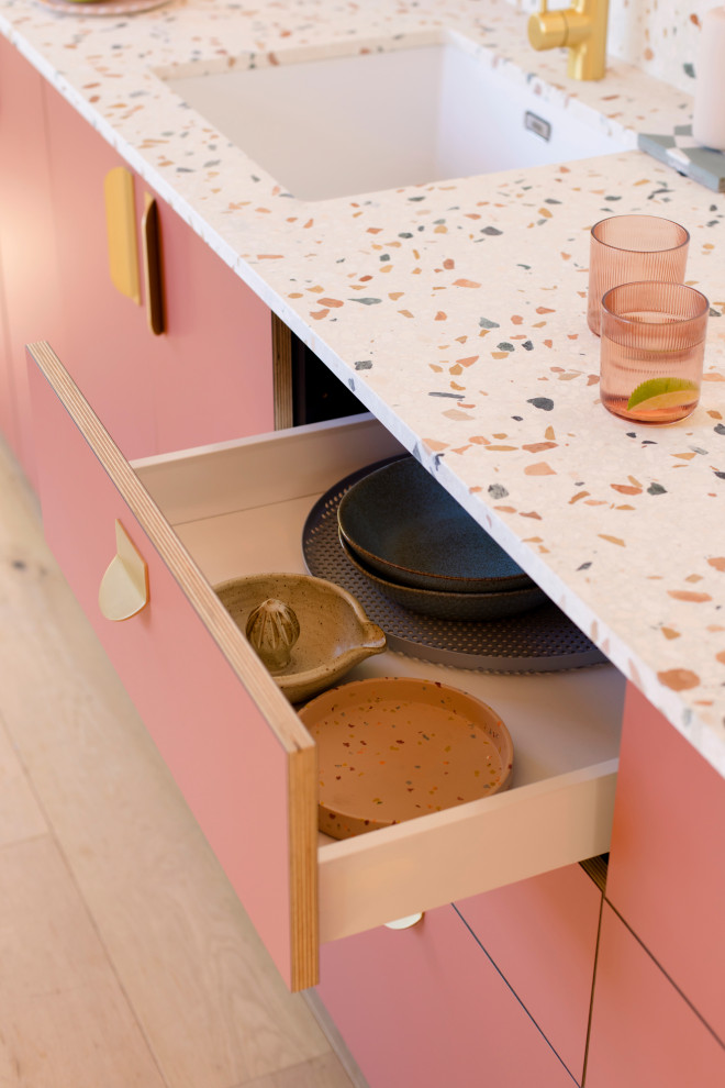 Пример оригинального дизайна: прямая кухня-гостиная в стиле модернизм с плоскими фасадами, розовыми фасадами, столешницей терраццо и разноцветной столешницей