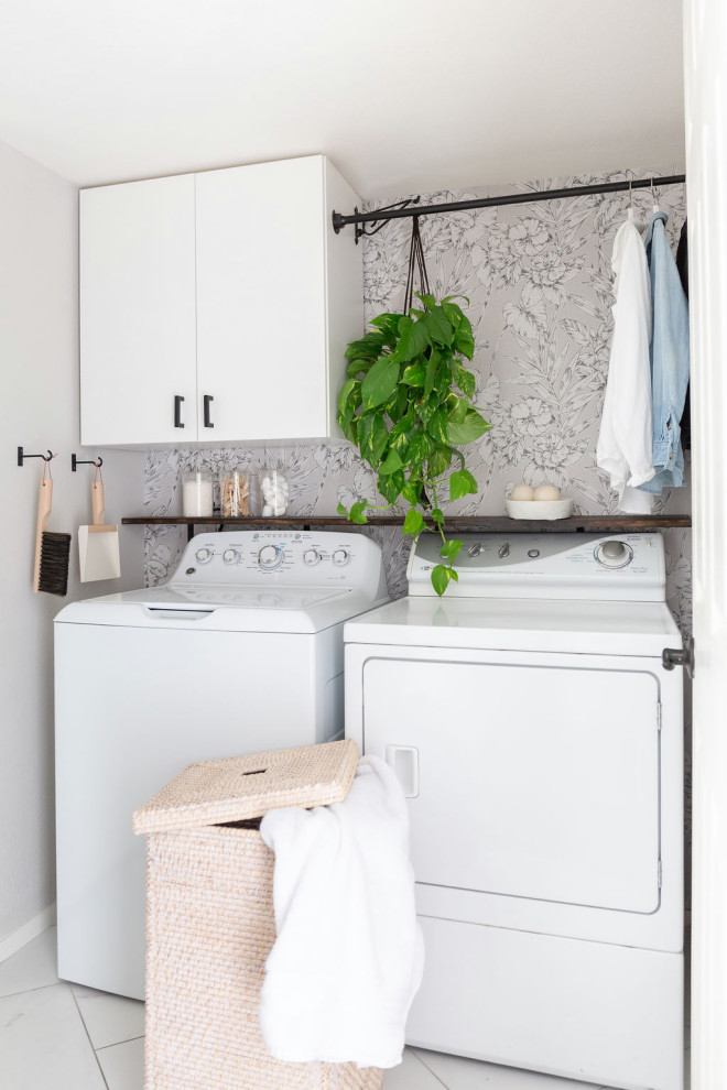 Immagine di una piccola sala lavanderia classica con ante lisce, ante bianche, pavimento con piastrelle in ceramica, lavatrice e asciugatrice affiancate, pavimento bianco e carta da parati