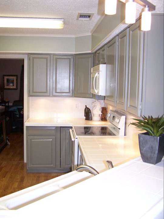 Inspiration for a mid-sized traditional l-shaped separate kitchen in Dallas with a double-bowl sink, grey cabinets, tile benchtops, white splashback, porcelain splashback, raised-panel cabinets, white appliances, medium hardwood floors and a peninsula.