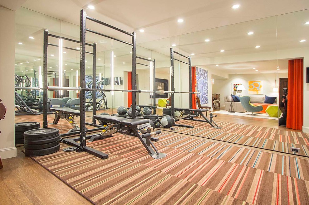 This is an example of a mid-sized modern home weight room in San Francisco with white walls, medium hardwood floors and brown floor.