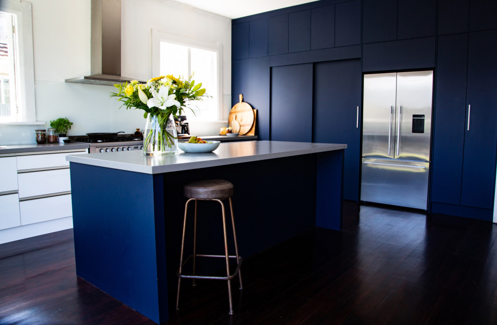 Inspiration for a large contemporary l-shaped eat-in kitchen in Napier-Hastings with an undermount sink, flat-panel cabinets, blue cabinets, quartz benchtops, white splashback, glass sheet splashback, stainless steel appliances, dark hardwood floors, with island, brown floor and white benchtop.