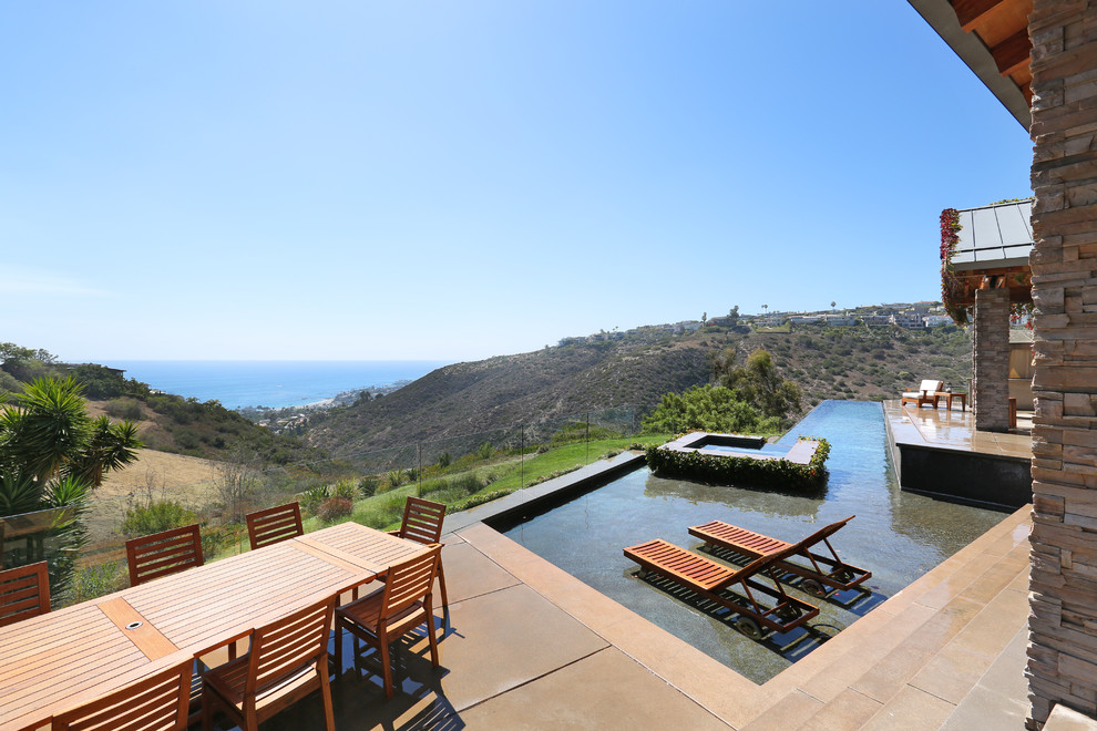 Photo of a contemporary custom-shaped infinity pool in Orange County with a hot tub.