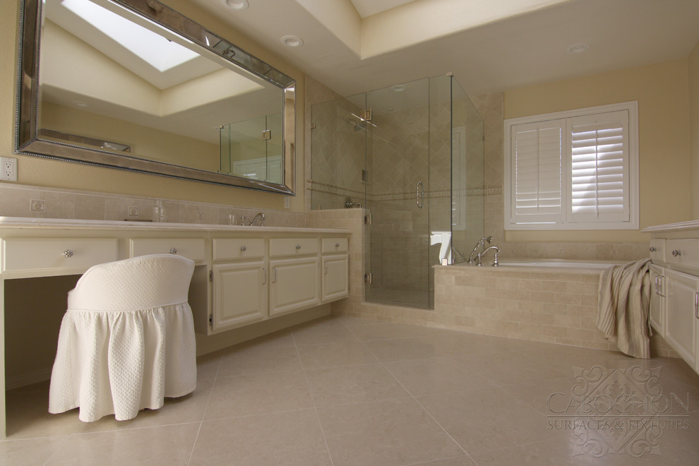 Inspiration for a mid-sized traditional master bathroom in San Diego with an undermount sink, a drop-in tub, a corner shower, a two-piece toilet, shaker cabinets, beige cabinets, beige tile, stone tile, beige walls and marble floors.