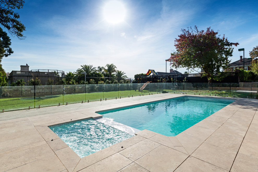 Mid-sized traditional rectangular pool in Melbourne with natural stone pavers.