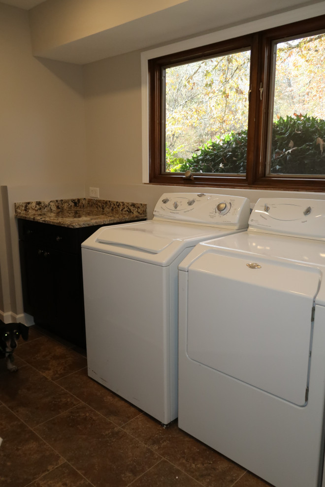 Design ideas for a mid-sized traditional single-wall dedicated laundry room in Other with shaker cabinets, black cabinets, granite benchtops, beige walls, ceramic floors, a side-by-side washer and dryer, brown floor and multi-coloured benchtop.