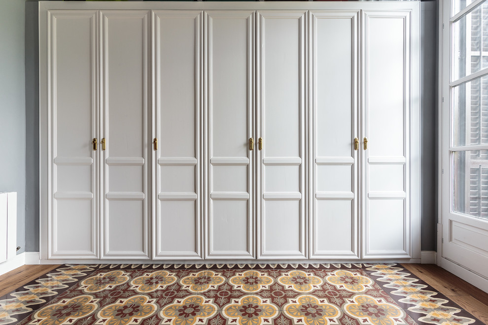 This is an example of a large transitional gender-neutral walk-in wardrobe in Barcelona with recessed-panel cabinets and white cabinets.