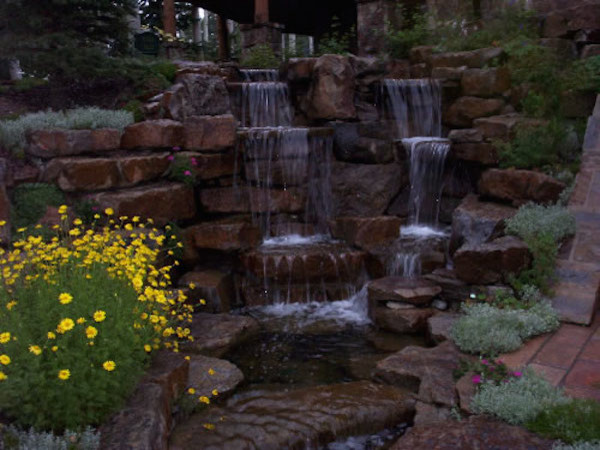 Photo of a huge rustic full sun backyard stone water fountain landscape in Denver.