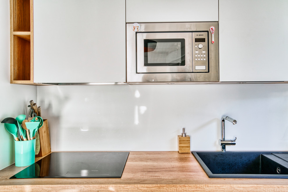 Esempio di una cucina minimalista di medie dimensioni con lavello da incasso, ante bianche e top in legno